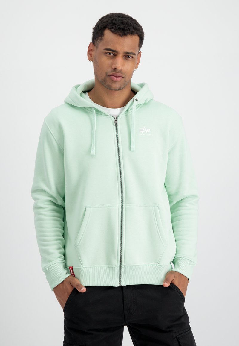 Felpa con zip di colore verde menta chiaro realizzata in morbido tessuto. Presenta una tasca frontale, coulisse e un piccolo logo bianco sul petto.