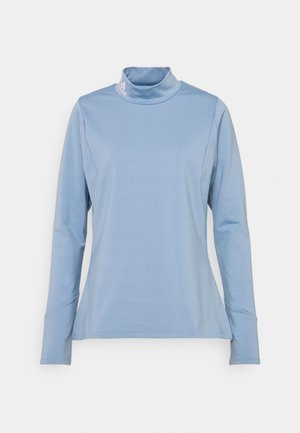 Lichtblauw sportief shirt met lange mouwen, een colshirt en een klein wit Adidas-logo op de kraag, plat neergelegd op een witte achtergrond.