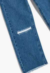 Jeans de mezclilla azul con recortes deshilachados en las rodillas, diseño de pierna recta y dobladillo sin acabar. La tela tiene una textura clásica desgastada.