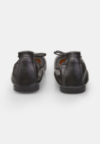 Black leather ballet flats with a rounded toe, small front bow detail, and a low, flat heel; smooth texture with subtle stitching.
