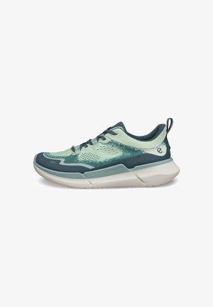 Scarpe da ginnastica verde chiaro e teal scuro con tomaia in rete, colletto imbottito, lacci e suola in gomma. Presentano un design con texture e una linguetta.