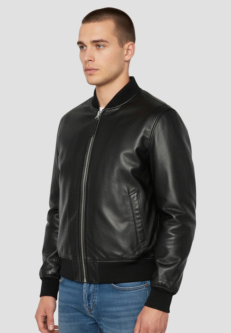 Blouson aviateur en cuir noir avec poignets et col côtelés, doté d'une fermeture éclair centrale et de deux poches latérales. Fini texturé.