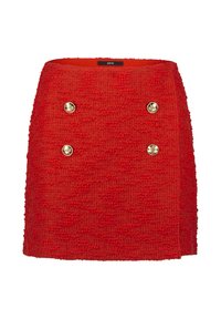Red knitted skirt with a textured surface, featuring two gold buttons on the front. Straight shape and a clean hem at the bottom.