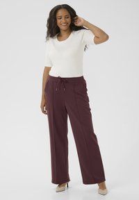 Burgundy wide-leg pants with a drawstring waist, made from soft fabric. Paired with a fitted white short-sleeve top.