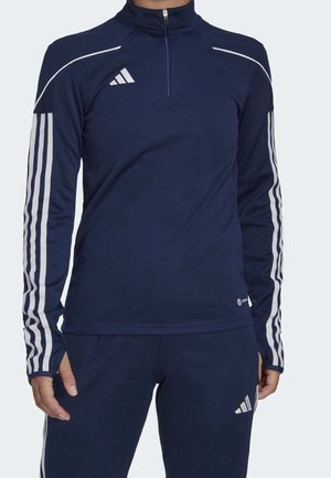 Granatowy dres Adidas z białymi paskami na rękawach i spodniach, z suwakiem do ćwierć długości na górze i logo na klatce piersiowej oraz udzie.