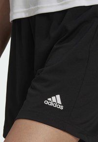 Black athletic shorts made of lightweight fabric, featuring a white Adidas logo on the lower left side. Smooth texture, elastic waistband.