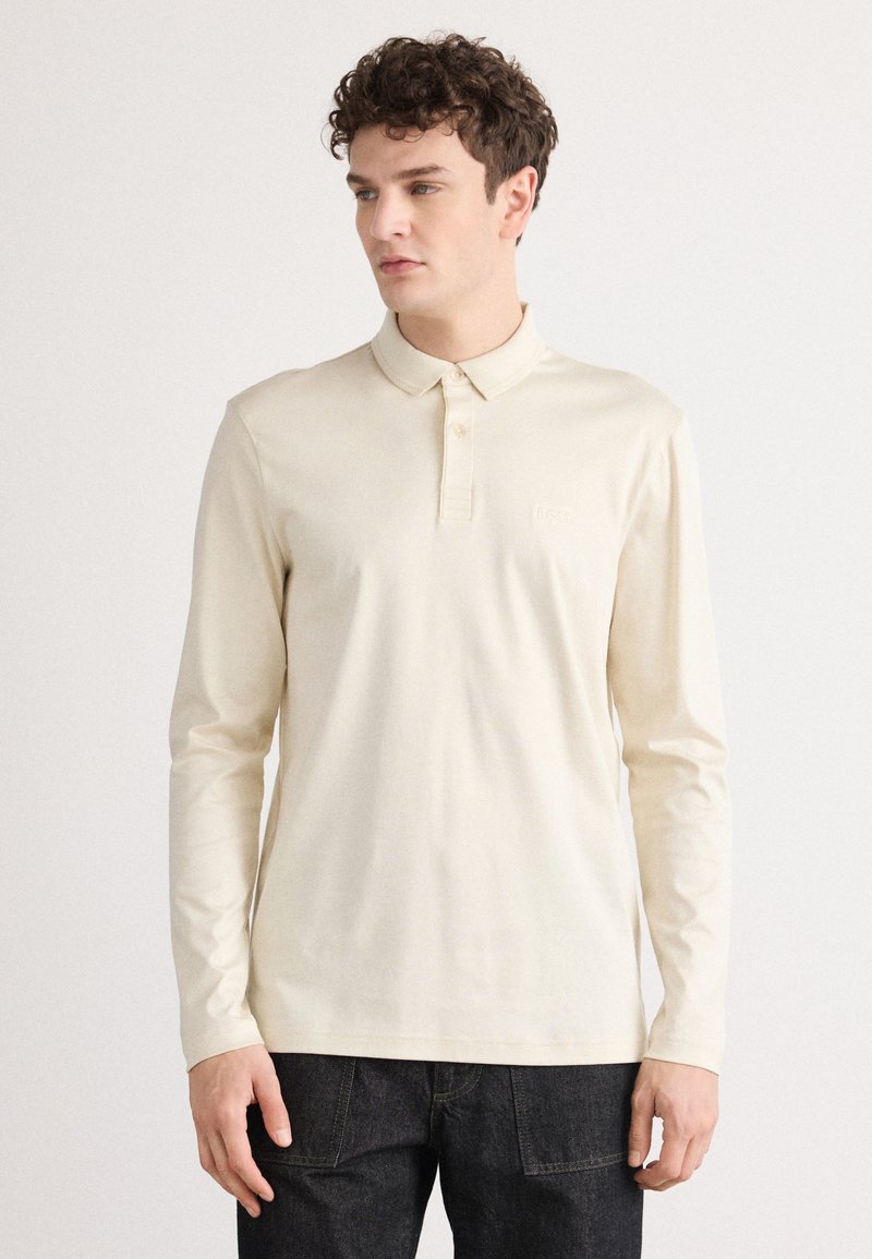 Korte mouwen polo shirt in lichtbeige katoen. Voorzien van een kraag, drie knopen en een subtiele logo op de borst.
