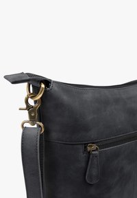 Schwarze Lederhandtasche mit glatter Textur, einem Reißverschluss oben und Messingbeschlägen, einschließlich einem abnehmbaren Tragegurt und Clip.