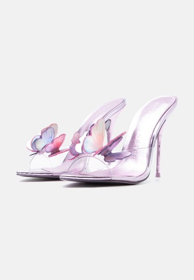 Ροζ μεταλλικά mules με ψηλά τακούνια και διαφανείς λουράκια διακοσμημένα με πεταλούδες σε παστέλ αποχρώσεις σε απλό ανοιχτό φόντο.