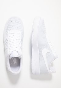 Vita Nike Air Force 1-sneakers med ett luftigt meshövre, vadderad krage, texturerad sula och klassisk swoosh-logotyp på sidan.