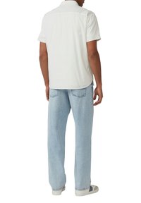Kortarmig shirt van witte stof, gecombineerd met lichtblauwe, losse jeans. Casual look met een eenvoudig ontwerp en een zachte textuur.