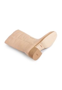 Μπέζ δερμάτινη μπότα μέχρι τον αστράγαλο με λεία επιφάνεια, ελαφριά υφή, ψηλό τακούνι και υφασμάτινη εξωτερική σόλα. Διαθέτει ελάχιστες ραφές.