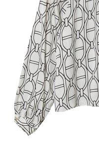 Blusa bianca con un motivo geometrico nero; presenta maniche lunghe e polsini con bottone. Tessuto liscio e leggero. Collo rotondo.