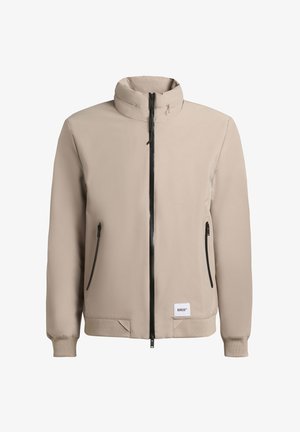 Beige kerge jakk kõrgema kaelusega, keskne must tõmblukk, kaks külgekotti ja elastsete mansettidega. Sile tekstuur, minimalistlik disain.