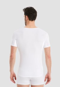 White short-sleeve fitted t-shirt made of smooth fabric, with a round neckline and subtle side seams, styled with white boxer briefs.