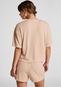 Lichtbeige gebreide top met korte mouwen en een ontspannen pasvorm, gecombineerd met bijpassende shorts. Zachte textuur met een casual ontwerp.