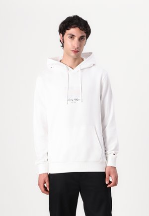 Biała hoodie wykonana z bawełny, z kieszenią z przodu, z kolorową łatą z logo na klatce piersiowej oraz ściągaczami przy mankietach i u dołu.
