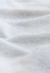 Soft, light gray cotton fabric with visible fine knit texture and gentle folds creating subtle shadows.
