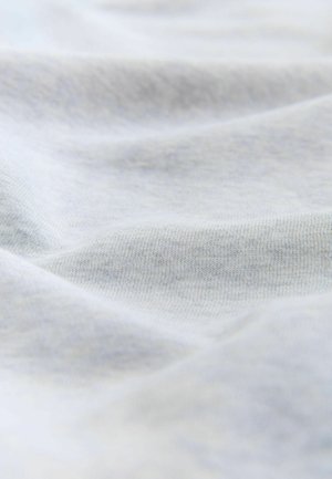 Pehmeä, vaalea harmaa puuvillakangas, jossa on näkyvä hieno neulepinta ja hellät taitteet, jotka luovat hienovaraisia varjoja.