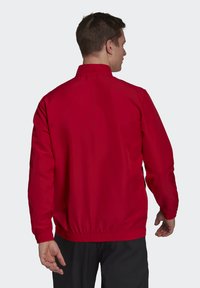 Rød jakke med høj krave og elastiske manchetter. Glat stof og løs pasform, med en samlet talje for et behageligt look.