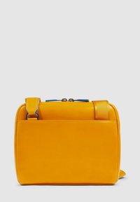 Sac à main jaune de forme rectangulaire, fabriqué en matériau lisse. Comprend une bandoulière détachable, une fermeture zippée sur le dessus et un design minimaliste.