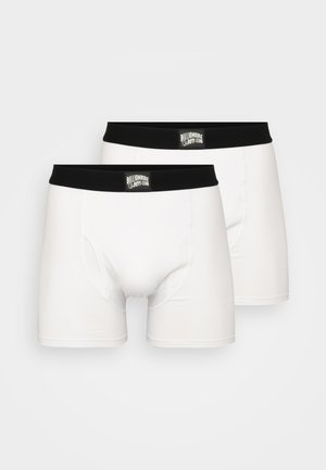 Deux paires de boxers blancs avec des ceintures élastiques noires portant une étiquette de logo. Le matériau semble lisse et élastique.