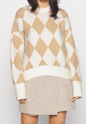 Beige en wit trui met argyle-patroon, gebreid met een geribbelde halslijn en manchetten, gecombineerd met een beige minirok met spikkels.