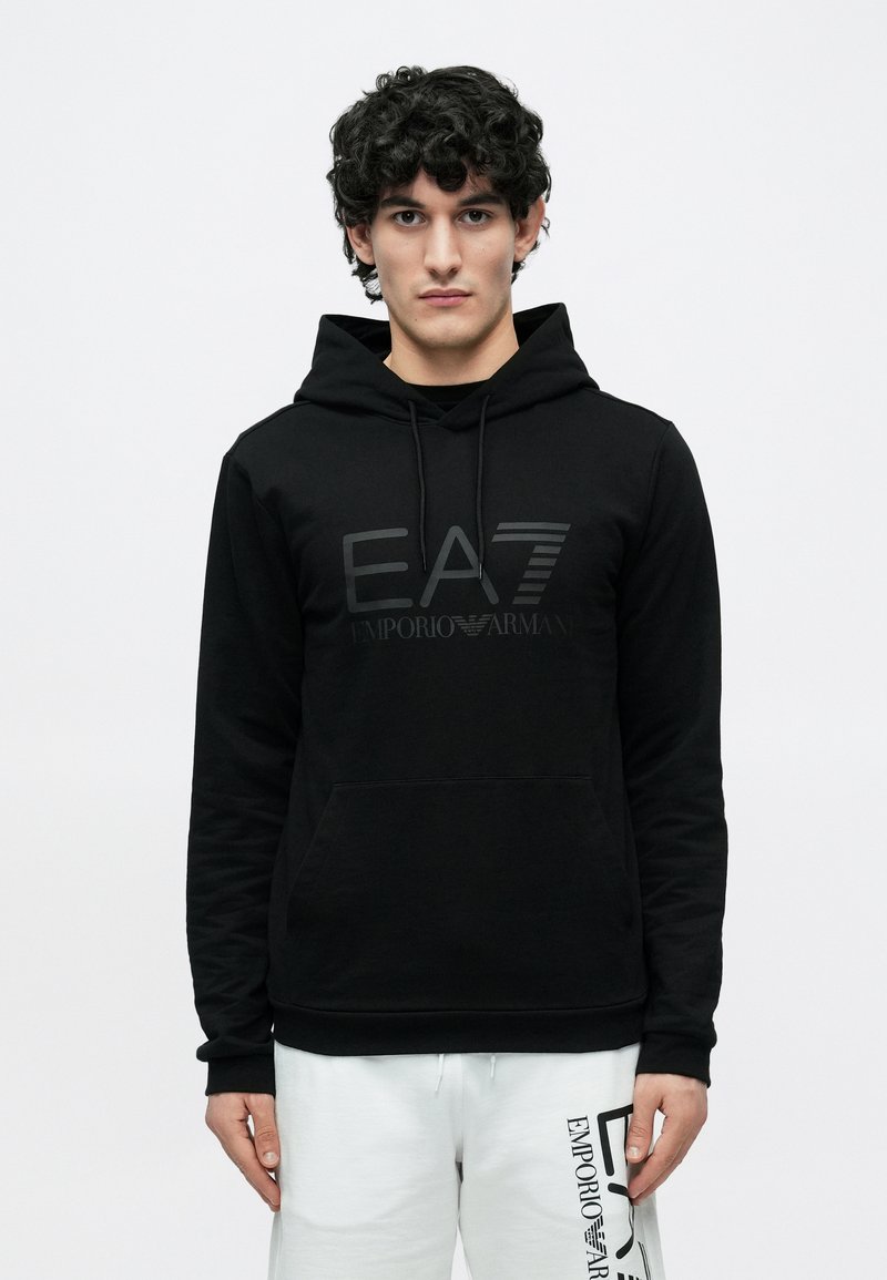 Svart hettegenser med kengurulomme, med et ton-i-ton EA7-logo og teksten "EMPORIO ARMANI". Mykt, glatt stoff med justerbar hette.