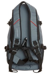 Grauer Rucksack mit schlankem Design, verstellbaren Riemen, seitlichen Netztaschen und roten Akzenten. Hergestellt aus strapazierfähigem Stoff mit glatter Textur.