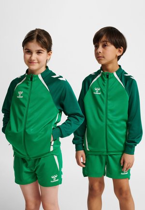 Grønne atletiske tracksuits med en zip-up jakke og shorts, med en kontrast hvid stribe og logo. Fremstillet af glat, strækbart materiale.