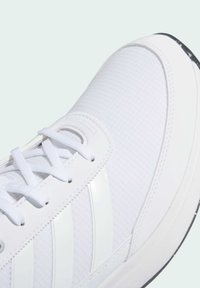 White athletic shoe with textured fabric upper, three glossy stripes, and white laces. Features a rubber sole with a black accent.