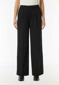 Black wide-leg trousers with an elastic waistband, featuring a smooth texture and side pockets. Material appears lightweight and flowy.