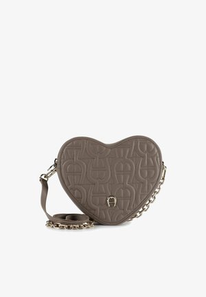 Herzförmige graue Lederhandtasche mit Steppmuster, ausgestattet mit einer goldfarbenen Kette und einem Riemen sowie einem auffälligen Logo-Akzent auf der Vorderseite.