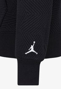 Felpa nera con texture a zigzag, caratterizzata da un logo Jumpman bianco sul polsino sinistro. Orlo e polsini a coste.
