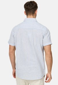 Camisa de manga corta en azul claro y rayas blancas. Fabricada con tejido transpirable, presenta un collar de punta y un dobladillo curvado. El diseño de la parte posterior incluye costuras horizontales.