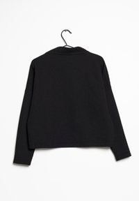 Mustapaita, jossa on pyöreä kaulus, pitkät hihat ja rento malli. Suunniteltu teksturoidusta kankaasta, mikä lisää syvyyttä.