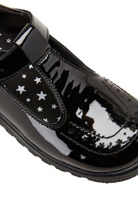 Schwarzer Lacklederschuh mit einem strukturierten schwarzen Stoffeinsatz, der weiße Sternmuster aufweist; Slip-On-Design mit runder Zehenform.