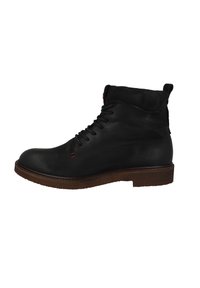 Botas de cuero negro hasta el tobillo con punta redonda, costuras de acentuación rojas y una suela marrón resistente. Presentan cordones y un cuello suave.