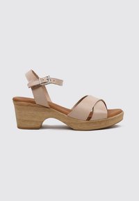 Sandalia de cuero beige con correas cruzadas, correa ajustable en el tobillo, superficie texturada y tacón de bloque de madera claro. Diseño cómodo.