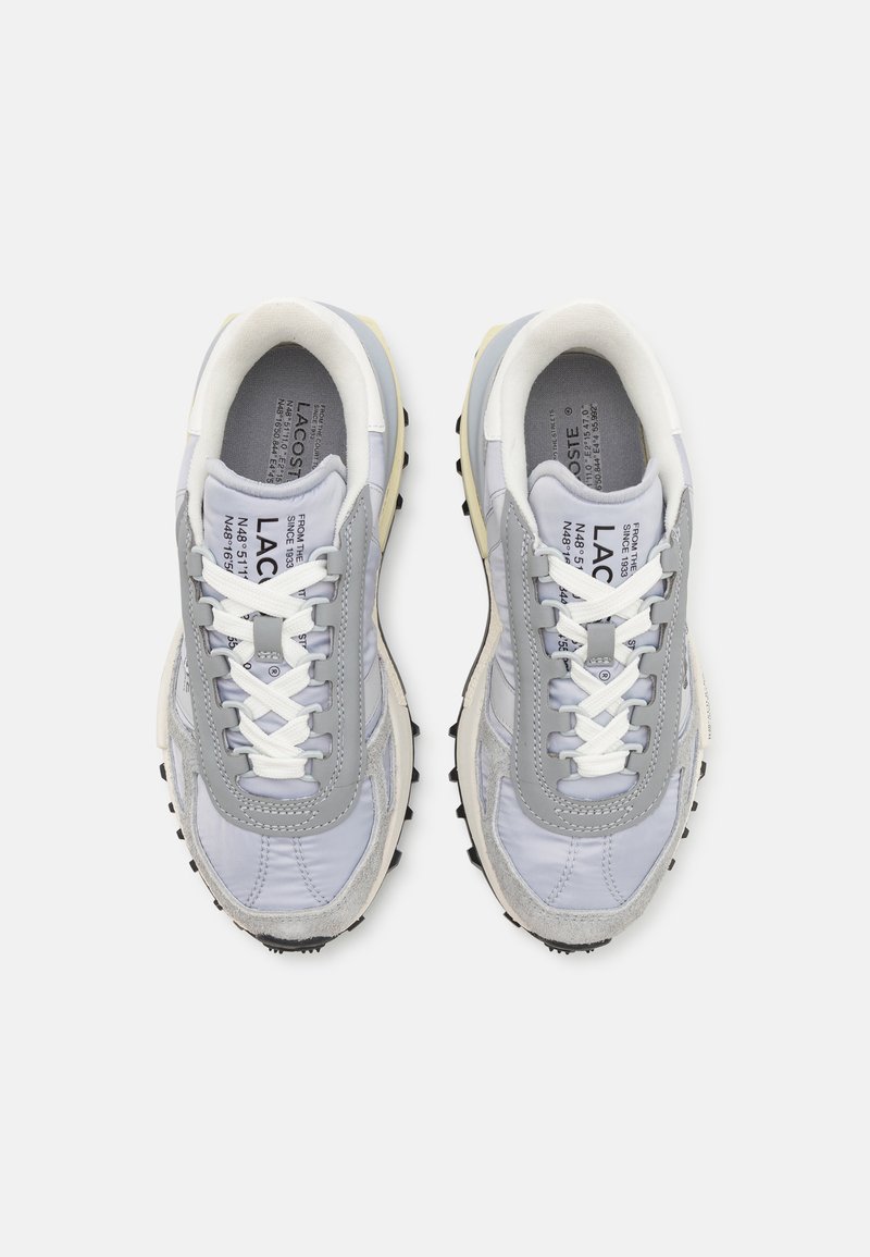 Sneaker grigie e bianche con una tomaia in materiali misti, caratterizzate da texture in camoscio e mesh, cuciture a zigzag e suola in gomma nera.