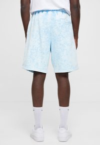 Lyseblå shorts med et tekstureret gradientmønster, der har en elastisk talje og sidelommer. Lavet af et blødt stof.