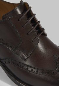 Bruine leren dansschoen met brogue-details, een gladde afwerking, zes veterogen en een ronde neus.