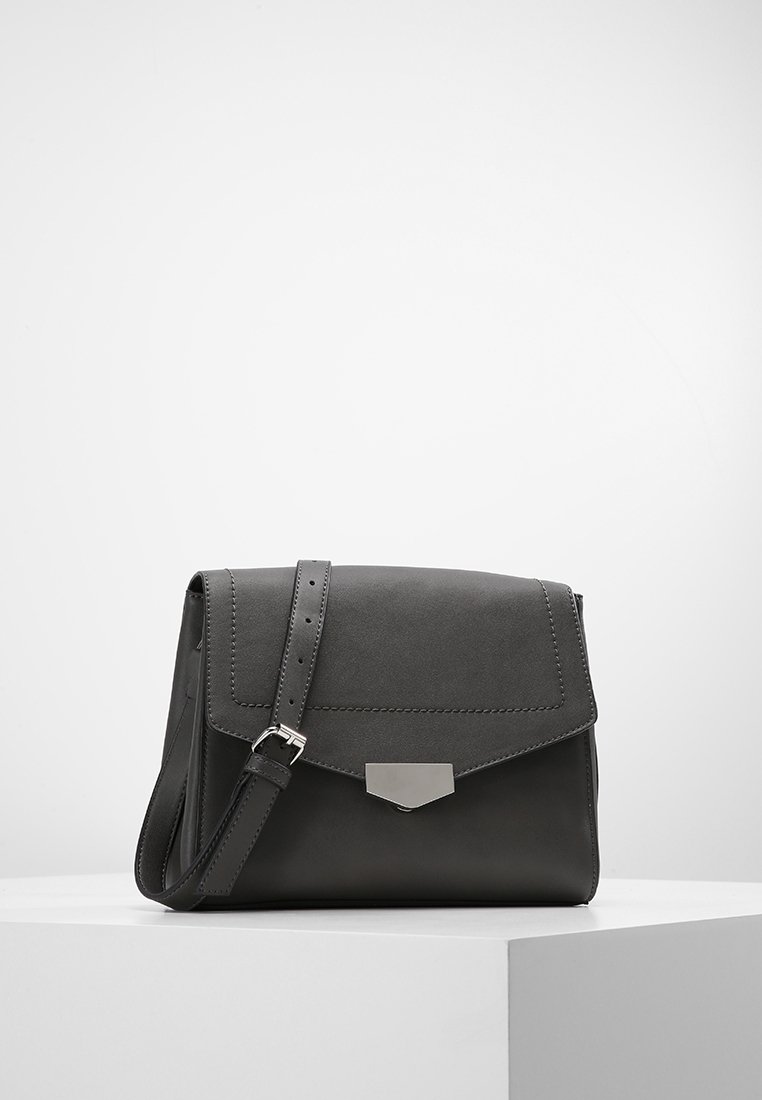 Borsa a tracolla in pelle nera con chiusura a patta, ferrature in argento e tracolla regolabile. Texture liscia con dettagli di cuciture visibili.