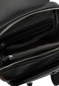 Interior de un bolso de cuero negro con múltiples compartimentos con cremallera y un forro texturizado. Presenta herrajes plateados y un diseño estructurado.