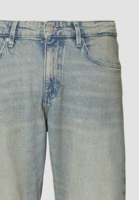 Jasnoniebieskie dżinsy o wyblakłym wzorze, pięcioma kieszeniami, z zapięciem na guzik i zamek błyskawiczny oraz lekko zwężającą się nogawką.