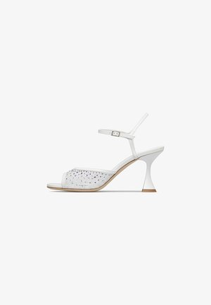 Sandalo bianco con tacco alto, cinturino alla caviglia, punta aperta, decorazioni scintillanti di strass sulla fascia anteriore e tacco sottile svasato.