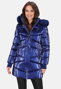 Sötétkék, fényes hatású steppelt kabát kapucnival, amely műszőrmével díszített, cipzáros záródású, és oldalán különleges varrásmintával ellátott zsebek találhatók.
