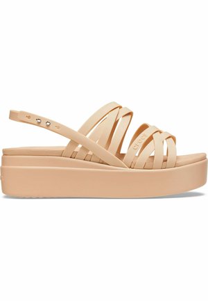 Peach-colored platform sandals with overlapping straps and a rounded toe. Made of rubber, featuring a textured sole and adjustable strap.