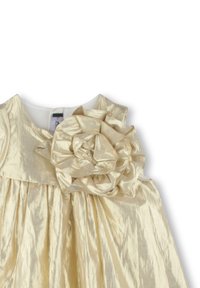 Robe couleur crème en tissu brillant avec un grand accent floral sur l'épaule gauche et une jupe plissée avec un décolleté rond.