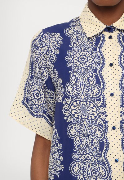 Camicia a maniche corte con bottoni caratterizzata da un motivo paisley blu e crema con pois, realizzata in tessuto leggero.